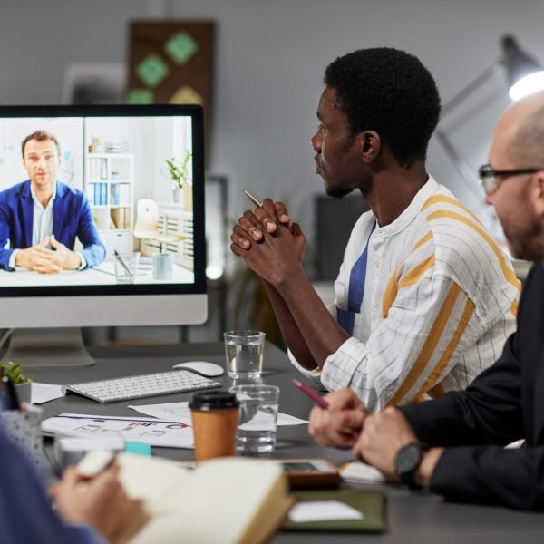 Businessman on computer screen talking to diverse team during online meeting in office